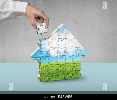 Assembling house shape puzzles on desk Stock Photo