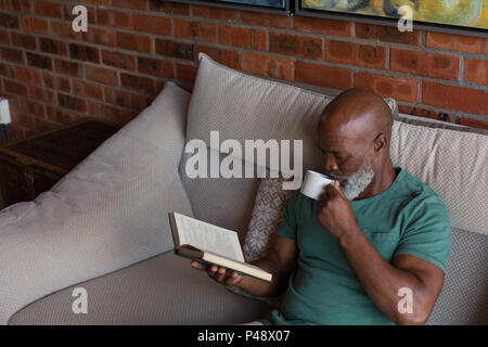 Senior man having coffee while reading a book Stock Photo