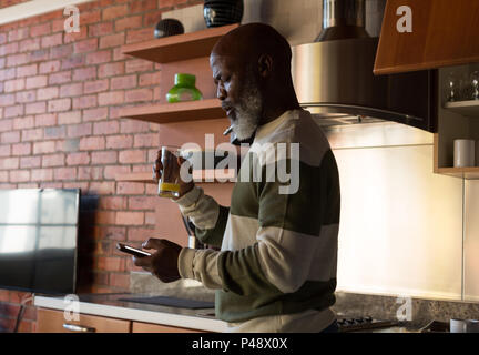 Senior man having juice while using mobile phone Stock Photo