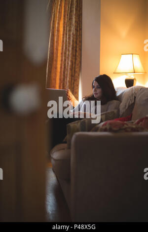 Female vlogger sitting on sofa while using laptop Stock Photo