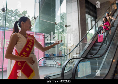 Young woman with welcoming message on sash directs visitors in hotel lobby, Quingadao, Shangdong Province, China. Stock Photo