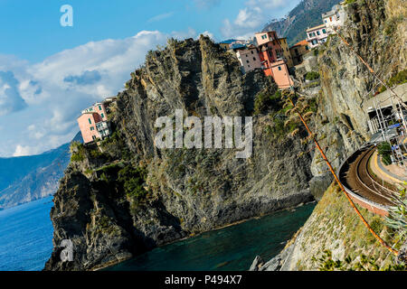 Tilted image of cliffs, sea and colorful cliff-sde homes seen from the train station, Manarola, Cinque Terre Stock Photo