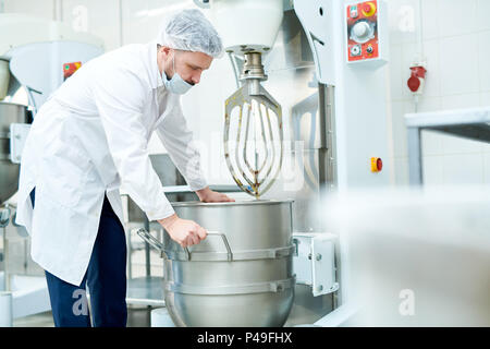 Confectionery factory employee working with machinery Stock Photo