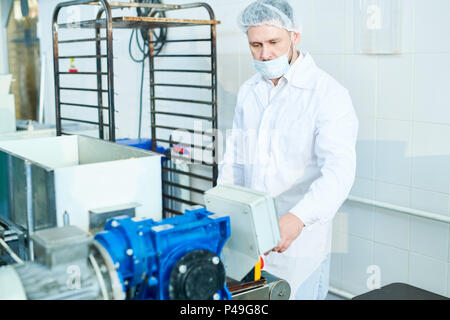 Confectioner working with machine at factory Stock Photo