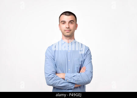 Portrait of happy fashionable handsome man in blue shirt crossing hands and look at camera. He is confident. Stock Photo