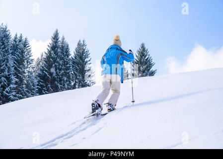 Woman is hiking with snowshoes on snow trail in winter landscape of forest in Oberstdorf, Bavaria Alps in South of Germany. Beautiful landscape with c Stock Photo