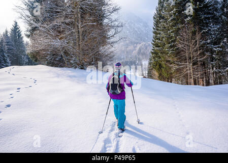 Hiker with snowshoes on snow trail in winter landscape of forest in Oberstdorf, Bavaria Alps in South of Germany. Beautiful landscape with coniferous Stock Photo