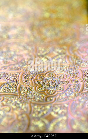 Silver, gold and copper ornamental filigree pattern in metallic vivid color with blurred background and selective focus. Copy space. Stock Photo