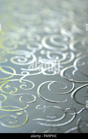 Light silver gray with gold ornamental filigree pattern in metallic vivid color with blurred background and selective focus. Copy space. Stock Photo