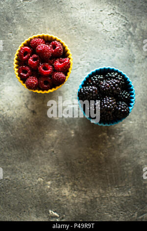 Raspberries and Blackberries in Ceramic Bowls on Rustic Background Stock Photo