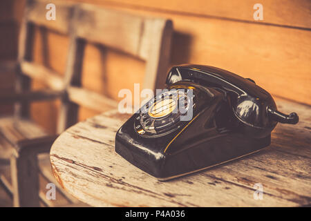 old telephone black color on wood table. classic retro vintage style rotary dial calling telephone type number.
