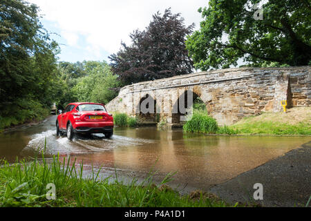 A stone footbridge over a ford in a typical english country village in summertime. Sutton, Bedfordshire Stock Photo