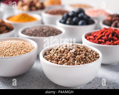 Hemp seeds in small white bowl and other superfoods on background. Selective focus. Different superfoods ingredients. Concept and illustration for superfood and detox food Stock Photo