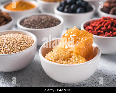 hive honey or honeycomb in small white bowl and other superfoods on background. Selective focus. Different superfoods ingredients. Concept and illustration for superfood and detox food Stock Photo