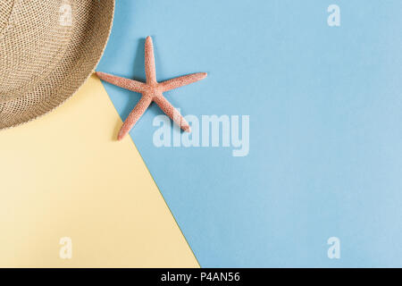 Part of straw hat and starfish on pastel blue-yellow background with copy space. Stock Photo