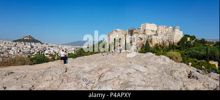 Athens, Greece - June 9, 2018: Panorama of tourists gazing at the Acropolis of Athens, Greece from a rocky hill across the Acropolis rock Stock Photo