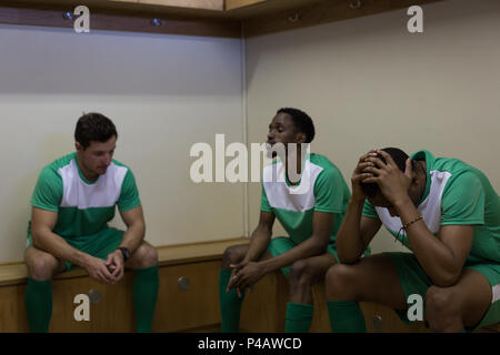 Football players sitting on dressing room Stock Photo