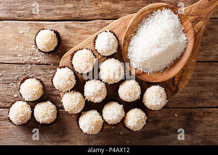 Brazilian Coconut Kisses (Beijinhos de Coco) condensed milk and coconut flakes close-up on the table. horizontal top view from above Stock Photo