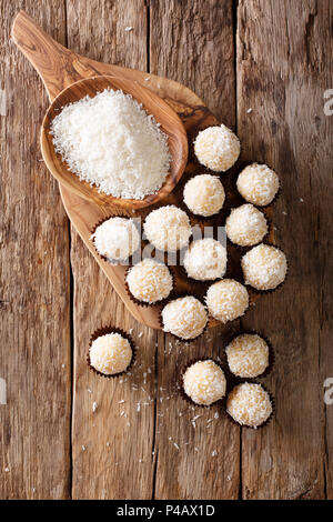 Delicious coconut kisses (beijinhos de coco or branquinhos)  - festive Brazilian sweets close-up on the table. Vertical top view from above Stock Photo