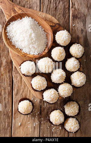 Brazilian Coconut Kisses (Beijinhos de Coco) condensed milk and coconut flakes close-up on the table. Vertical top view from above Stock Photo