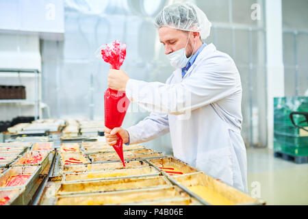 Concentrated confectioner using pastry bag at factory Stock Photo