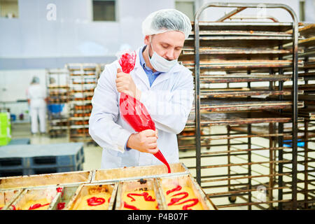 Confectionery factory employee using icing bag Stock Photo