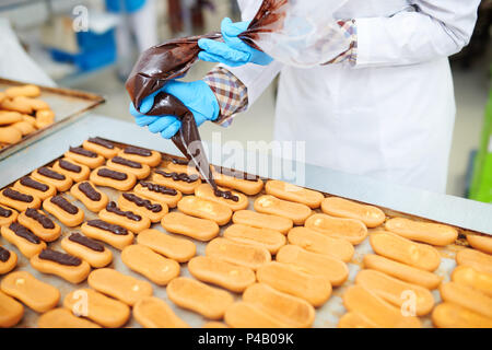 Confectioner decorating pastry using icing bag Stock Photo