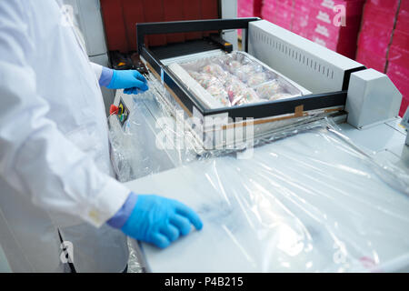Confectionery factory employee sealing box with packaging film Stock Photo