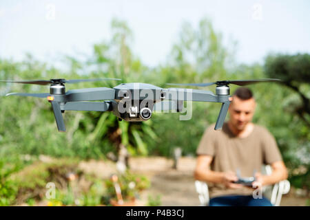 closeup of a caucasian man operating a drone, remotely controlled with a smartphone, in a natural landscape Stock Photo
