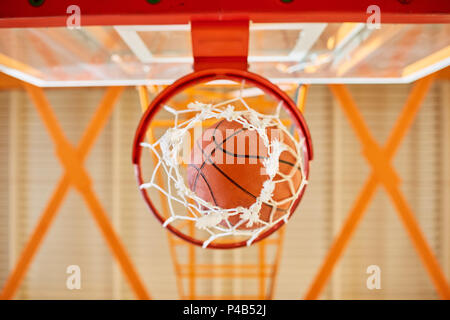 Ball falling through basketball basket Stock Photo