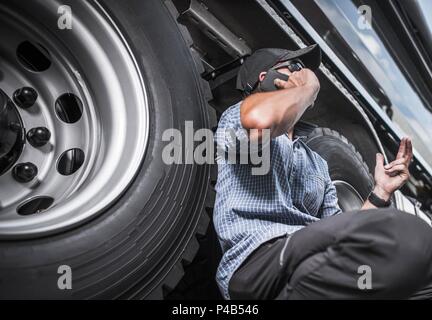 Truck Driving Business Concept. Caucasian Trucker on the Phone Next to His Vehicle. Stock Photo