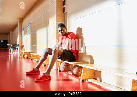 Black basketball player resting on bench Stock Photo