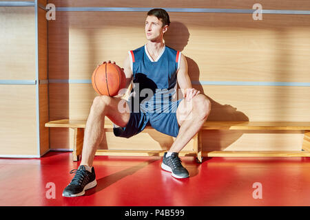 Basketball player resting on bench Stock Photo
