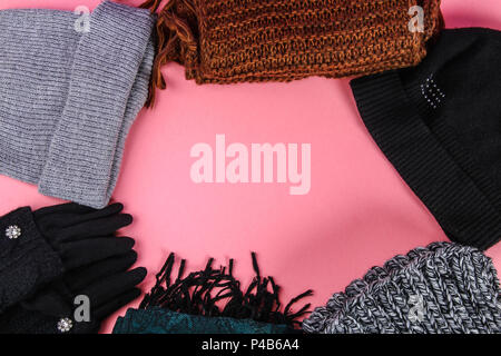 Winter and autumn clothes, hats, scarves, gloves on a purple pastel background Stock Photo