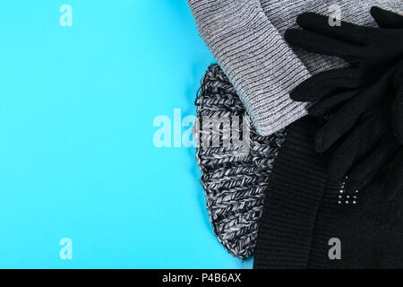 Winter and autumn clothes, hats, scarves, gloves on a blue pastel background Stock Photo