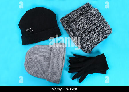 Winter and autumn clothes, hats, scarves, gloves on a blue pastel background Stock Photo