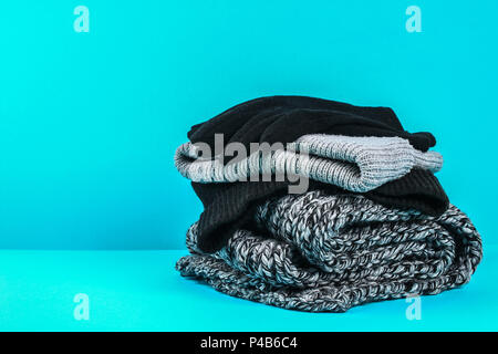 Winter and autumn clothes, hats, scarves, gloves on a blue pastel background Stock Photo