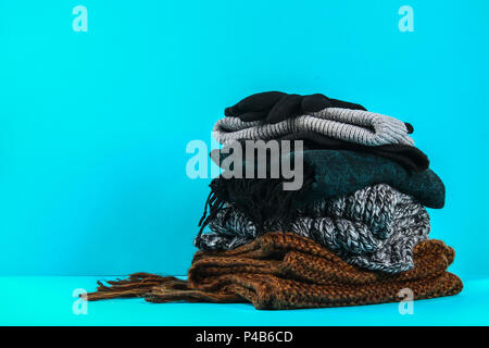 Winter and autumn clothes, hats, scarves, gloves on a blue pastel background Stock Photo
