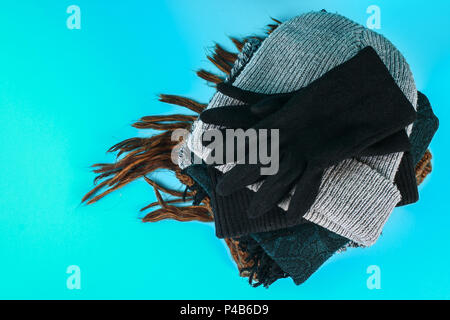 Winter and autumn clothes, hats, scarves, gloves on a blue pastel background Stock Photo