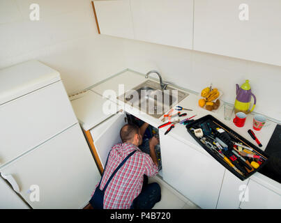Worker repairs the leakage problem in the kitchen sink Stock Photo