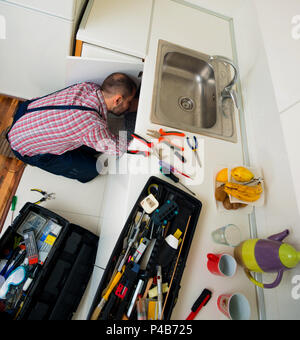 Worker repairs the leakage problem in the kitchen sink Stock Photo