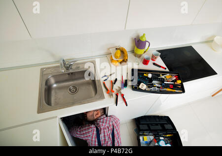 Worker repairs the leakage problem in the kitchen sink Stock Photo