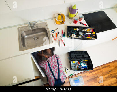 Worker repairs the leakage problem in the kitchen sink Stock Photo