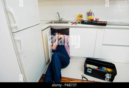 Worker repairs the leakage problem in the kitchen sink Stock Photo