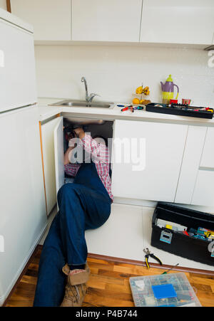 Worker repairs the leakage problem in the kitchen sink Stock Photo