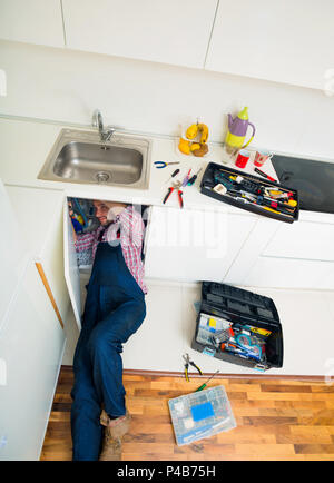 Worker repairs the leakage problem in the kitchen sink Stock Photo