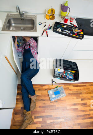 Worker repairs the leakage problem in the kitchen sink Stock Photo