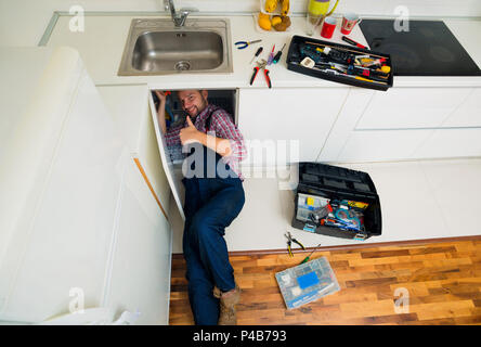 Worker repairs the leakage problem in the kitchen sink Stock Photo