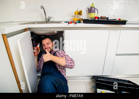 Worker repairs the leakage problem in the kitchen sink Stock Photo