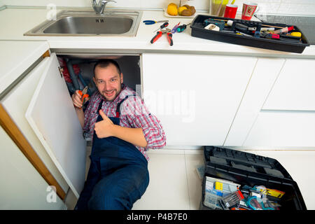 Worker repairs the leakage problem in the kitchen sink Stock Photo